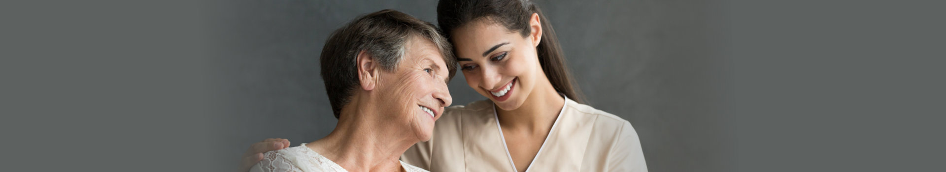 Friendly relationship between smiling caregiver in uniform and happy elderly woman